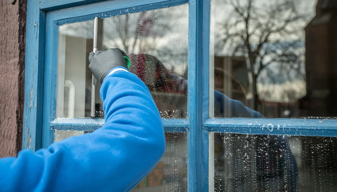 window cleaner washing glass with squeegee